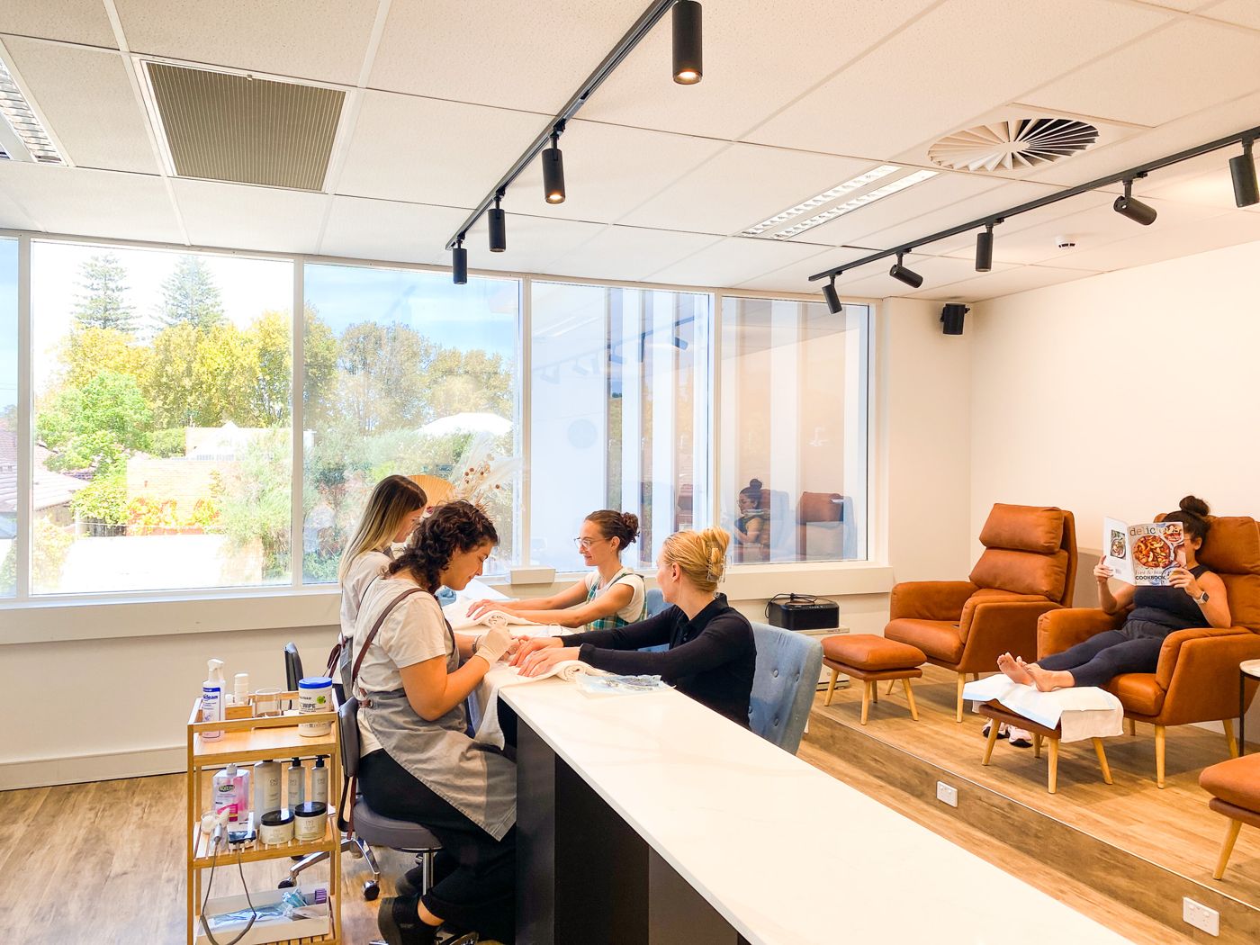 Nail therapists at work in The Foot Studio nail hub, with clients relaxing in the pedicure chairs