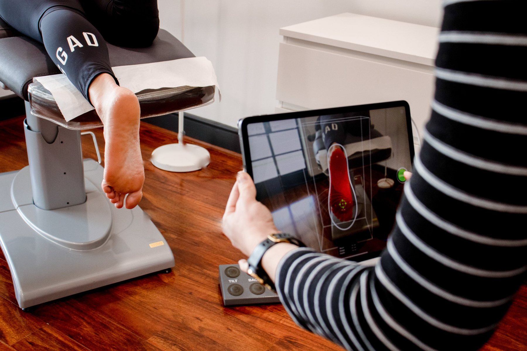 Podiatrist taking a 3D scan of a patient&rsquo;s foot on a tablet