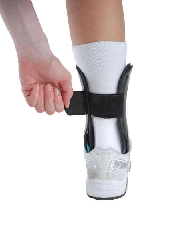 Fastening the strap of a Richie Brace over a sock and shoe