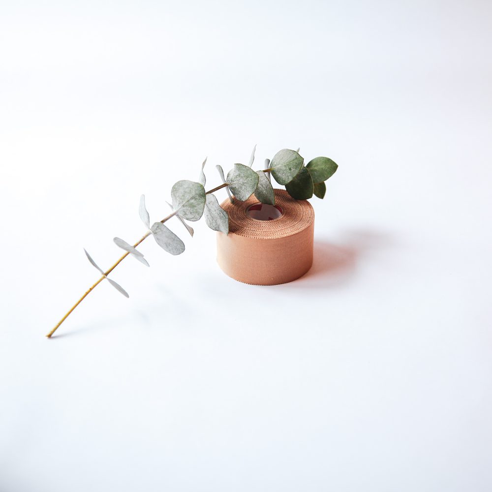 Roll of rigid sports tape with a eucalyptus sprig